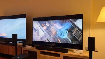65-дюймовый телевизор Sony Bravia 5 на деревянной тумбе, на экране — сцена из фильма «Охотники за привидениями: Ледяное царство»