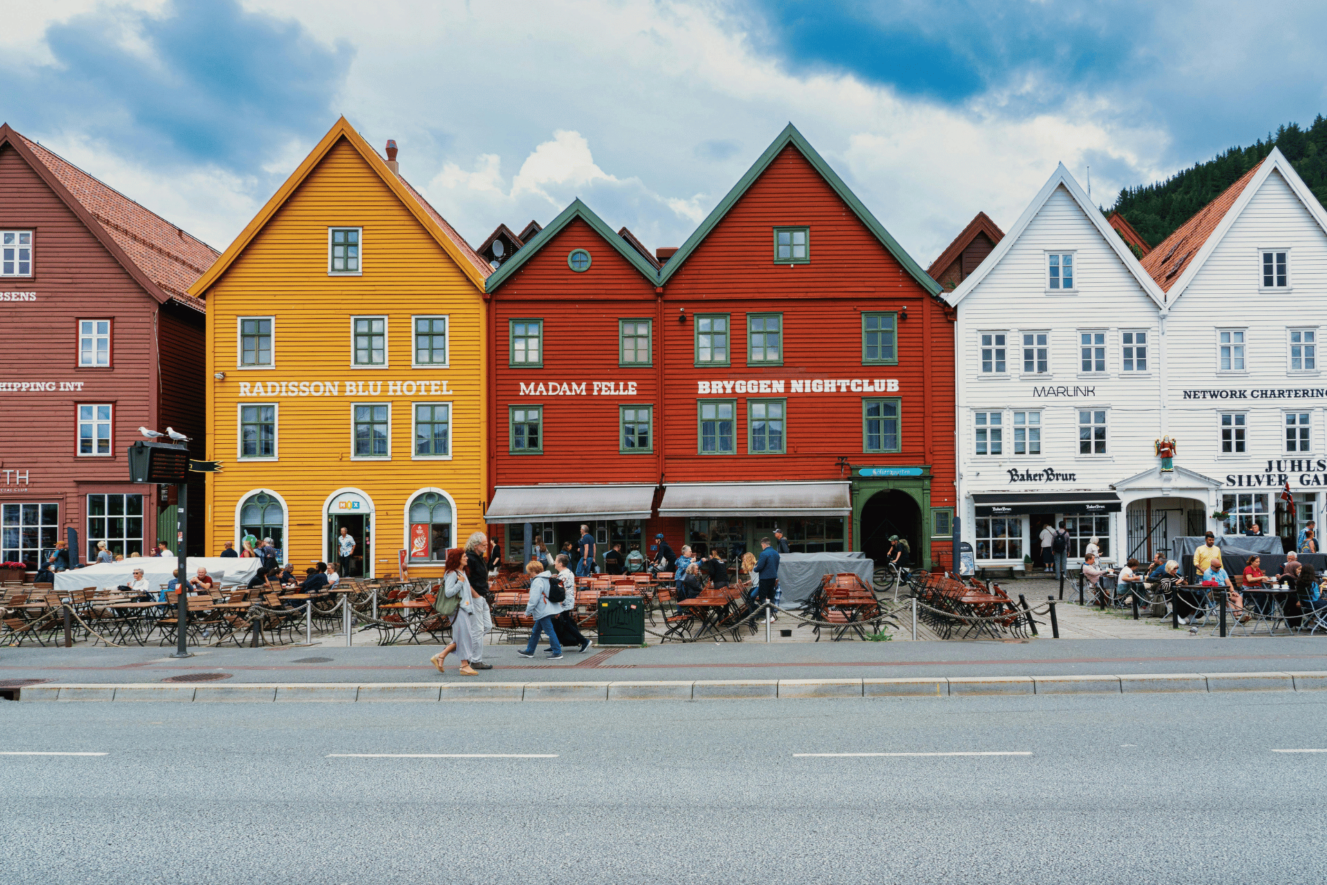 Foto av Bryggen i Bergen med fortausrestauranter i forgrunnen.