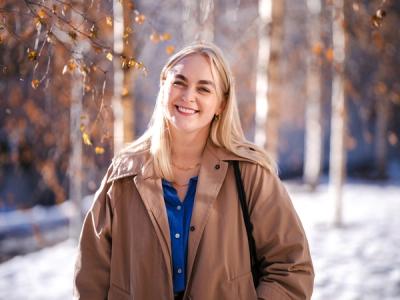 Bilde av ung dame som smiler. Snø i bakgrunn