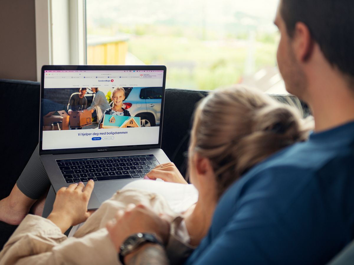 Ungt par i sofa ser på en mac-skjerm sammen. Foto