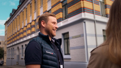 Eiendomsmegler prater med kunder utenfor bygård på Lademoen.