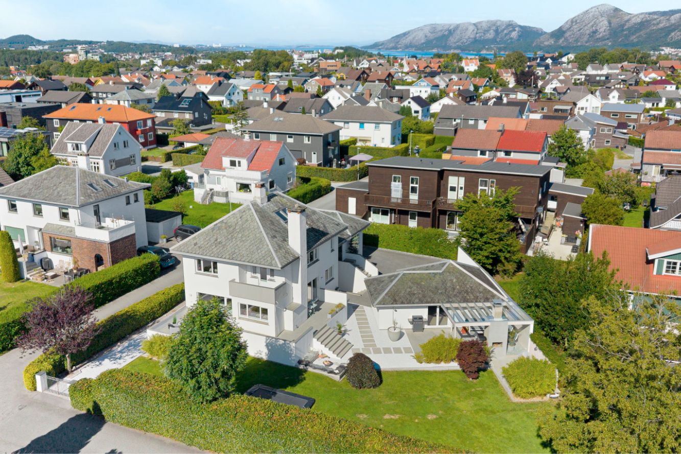 Oversiktsbilde av hele tomten og boligen med nabolaget i bakgrunnen