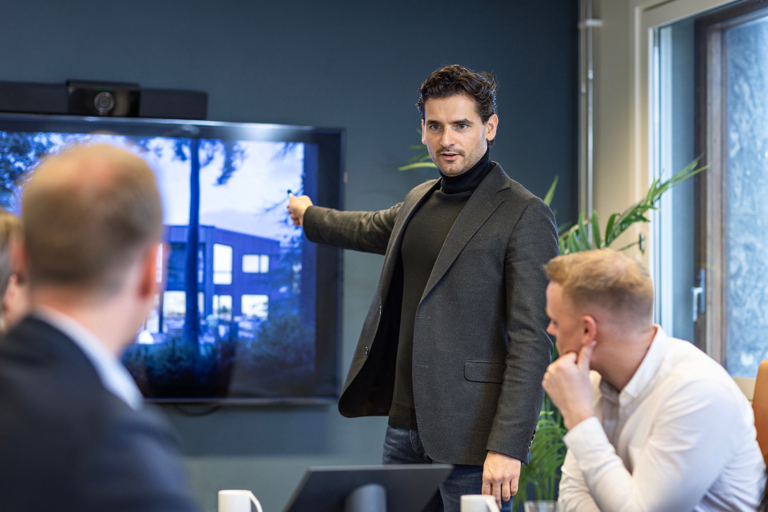 Eiendomsmegler presenterer boligmarked og salgstall for kolleger på kontoret.