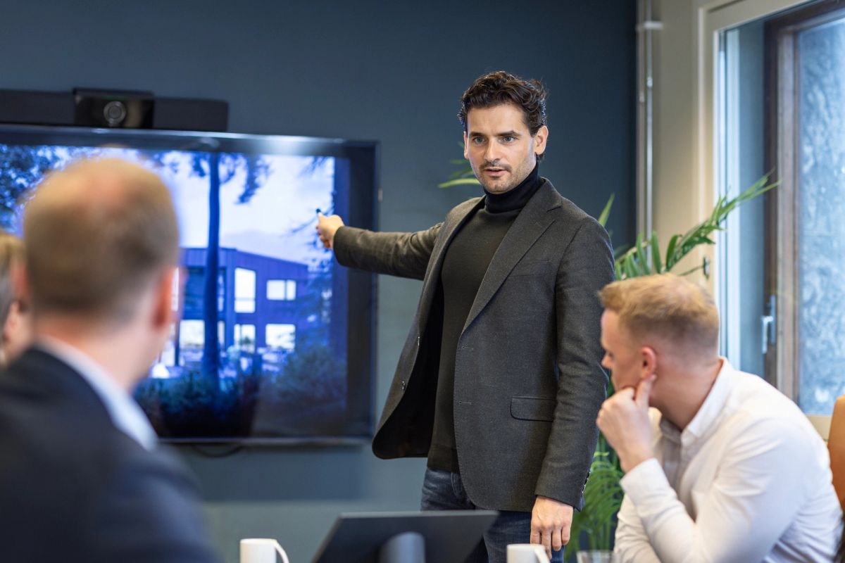 Eiendomsmegler presenterer boligmarked og salgstall for kolleger på kontoret.