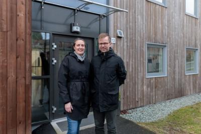Foto av mann og kvinne som står utenfor inngangsdøren til et leilighetsbygg.