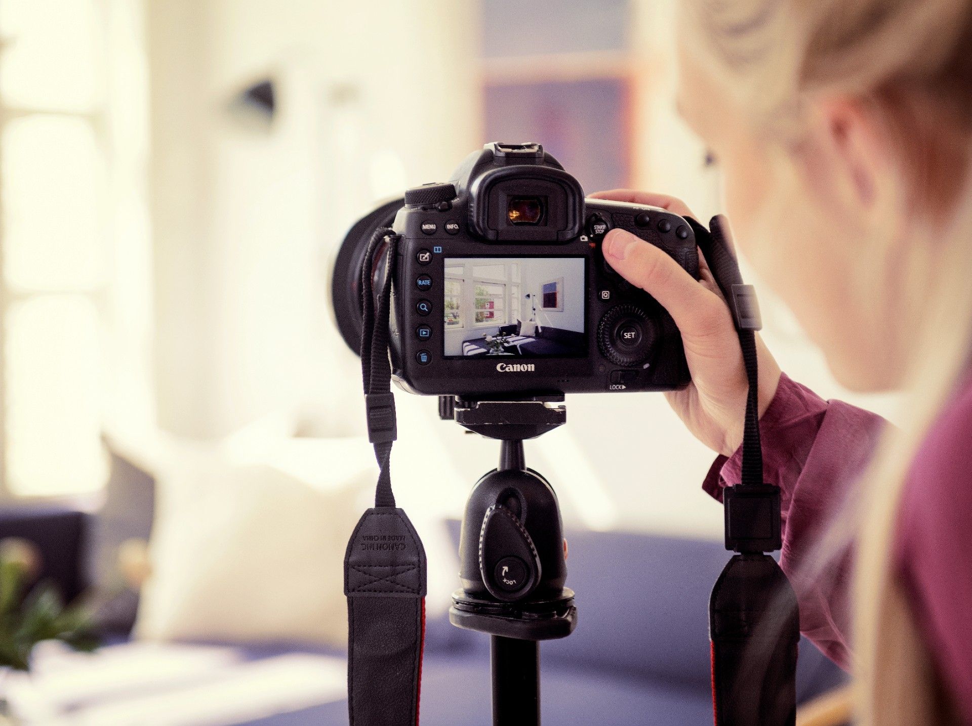 Fotoapparat med skjermen i fokus, tar interiørbilde. Jente holder i kamera. Foto.