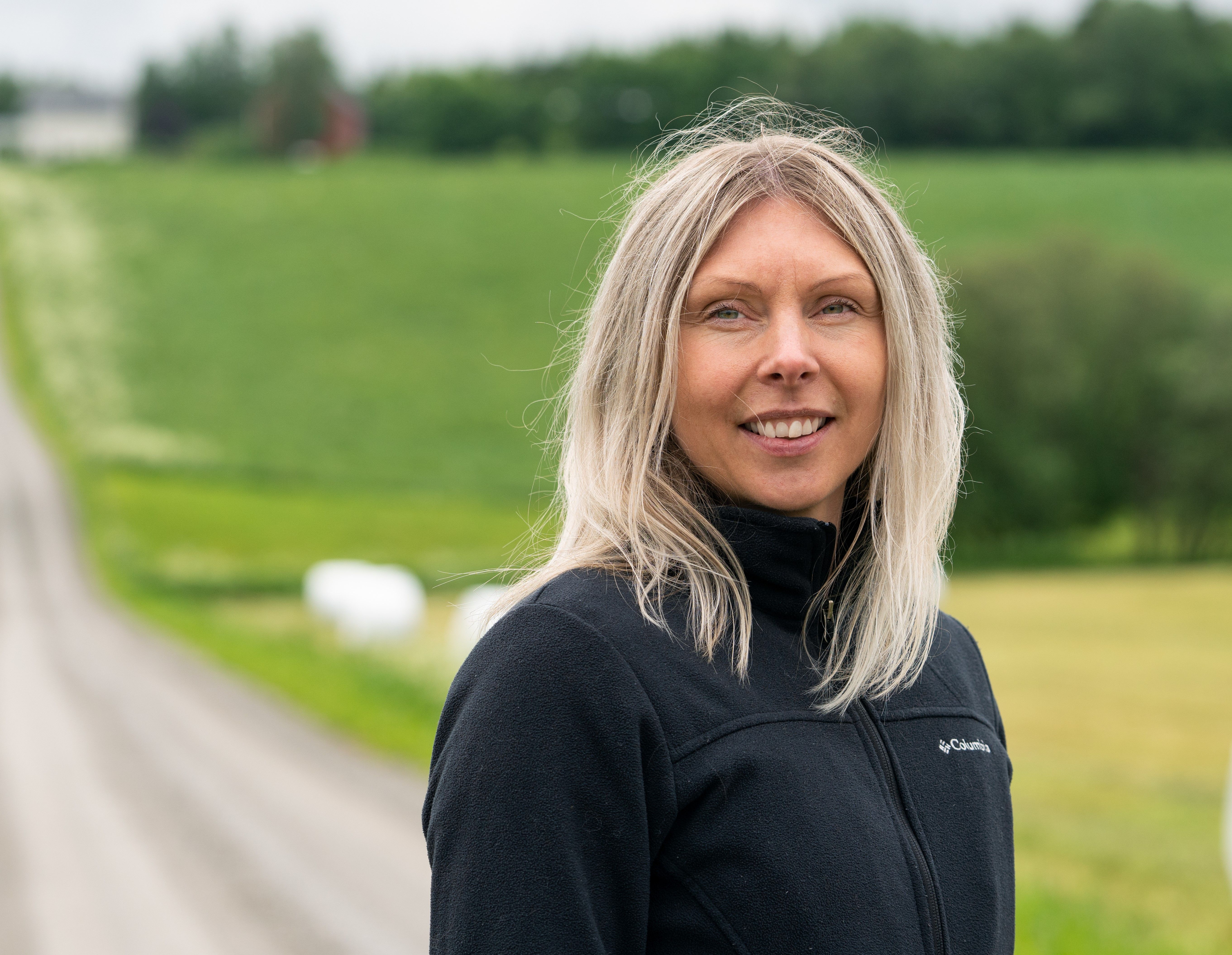 Landbruksrådgiver fra SpareBank 1 som står på en grusvei ved et jorde.