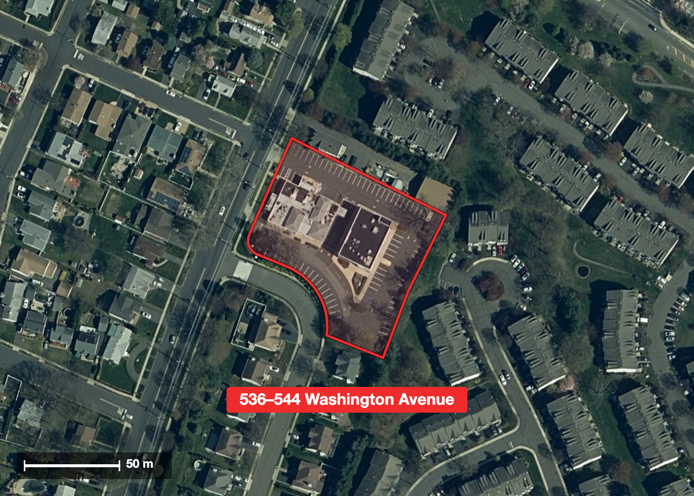 Aerial photograph of 536–544 Washington Avenue with the lot boundary outlined in red, showing the two commercial buildings and their parking lot surrounded on every side by detached houses and garden apartments.