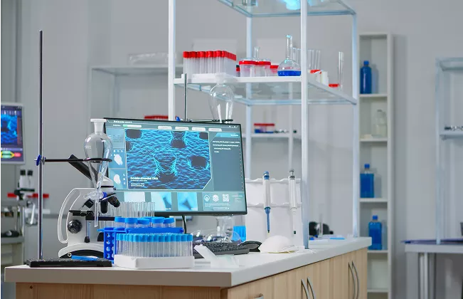 Modern laboratory with scientific equipment, computer displaying molecular analysis, and test tubes organized on shelves and a counter.
