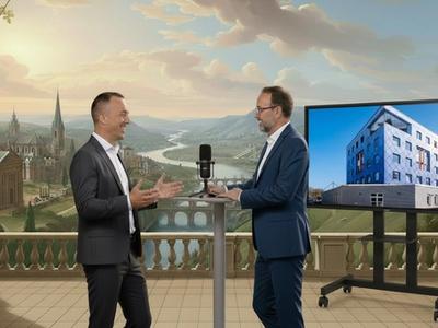 Zwei Geschäftsleute diskutieren Immobilienprojekte vor einer historischen Panoramakulisse und einem Bildschirm mit Gebäudeansicht.