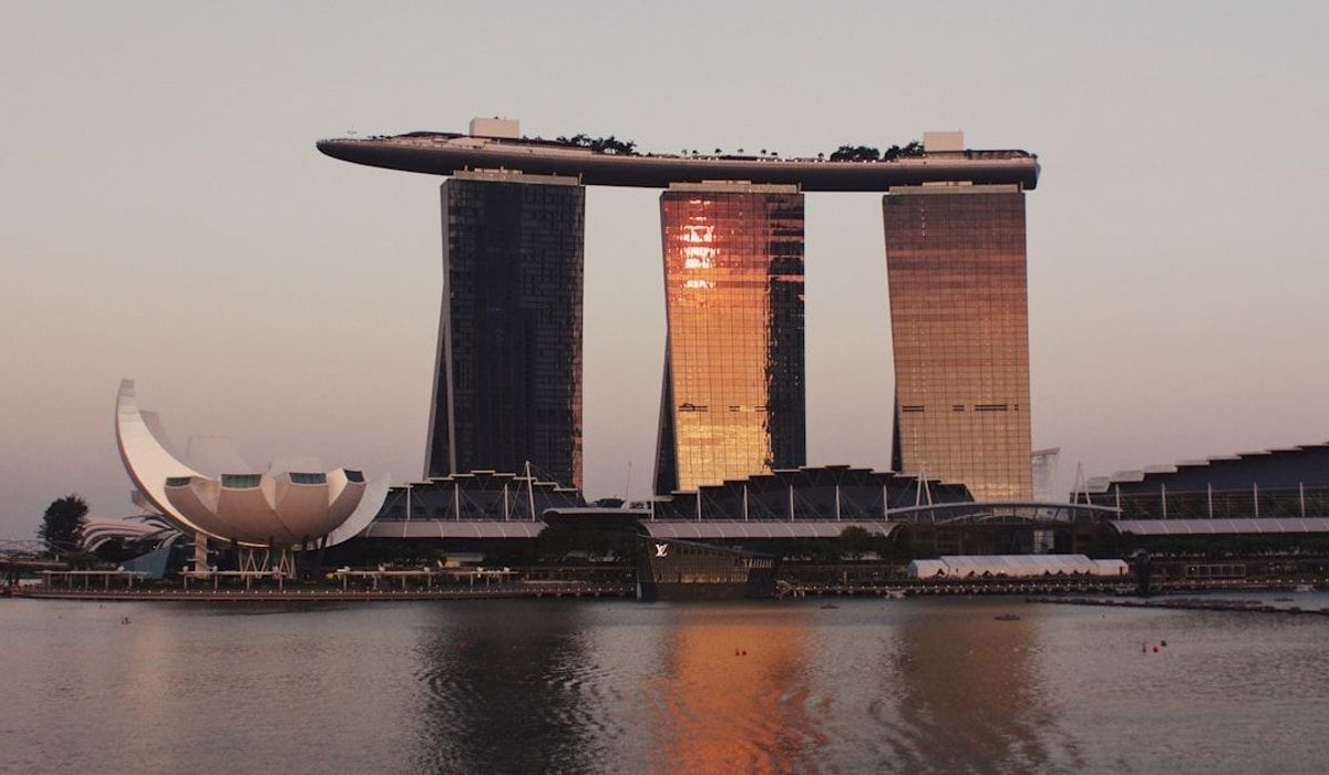 Singapore waterfront skyline at dusk with warm golden light reflecting on the bay
