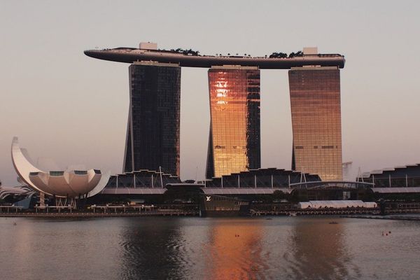 Singapore waterfront skyline at dusk with warm golden light reflecting on the bay