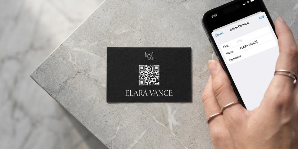 A matte-black business card with a white QR code on it next to an iPhone showing the iOS ‘Add to Contacts’ sheet