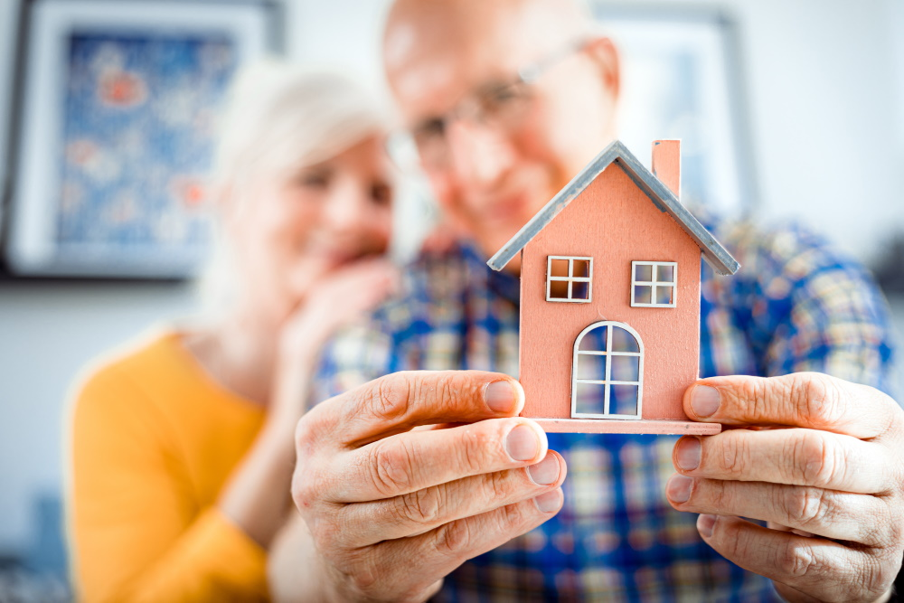 An older couple holding a model of a house