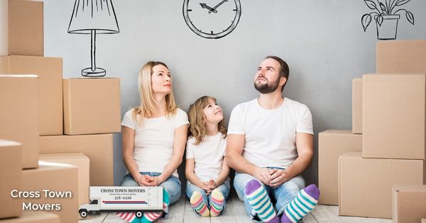 An exhausted family surrounded by moving boxes | Cross Town Movers