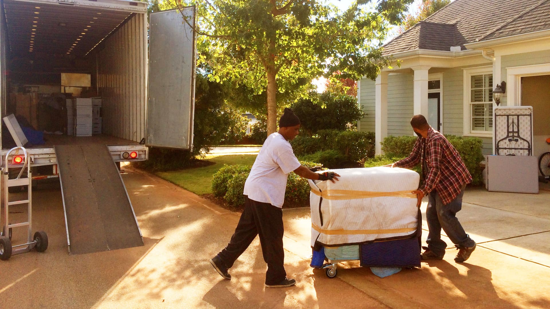 2 movers moving furniture into a house