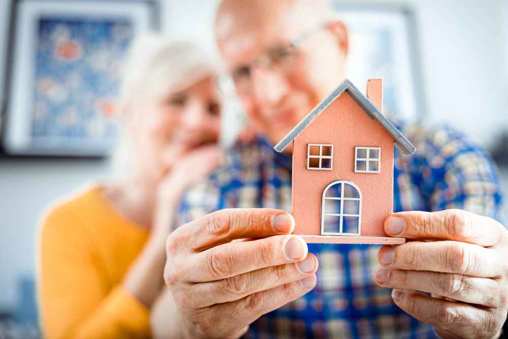 An older couple holding a model of a house
