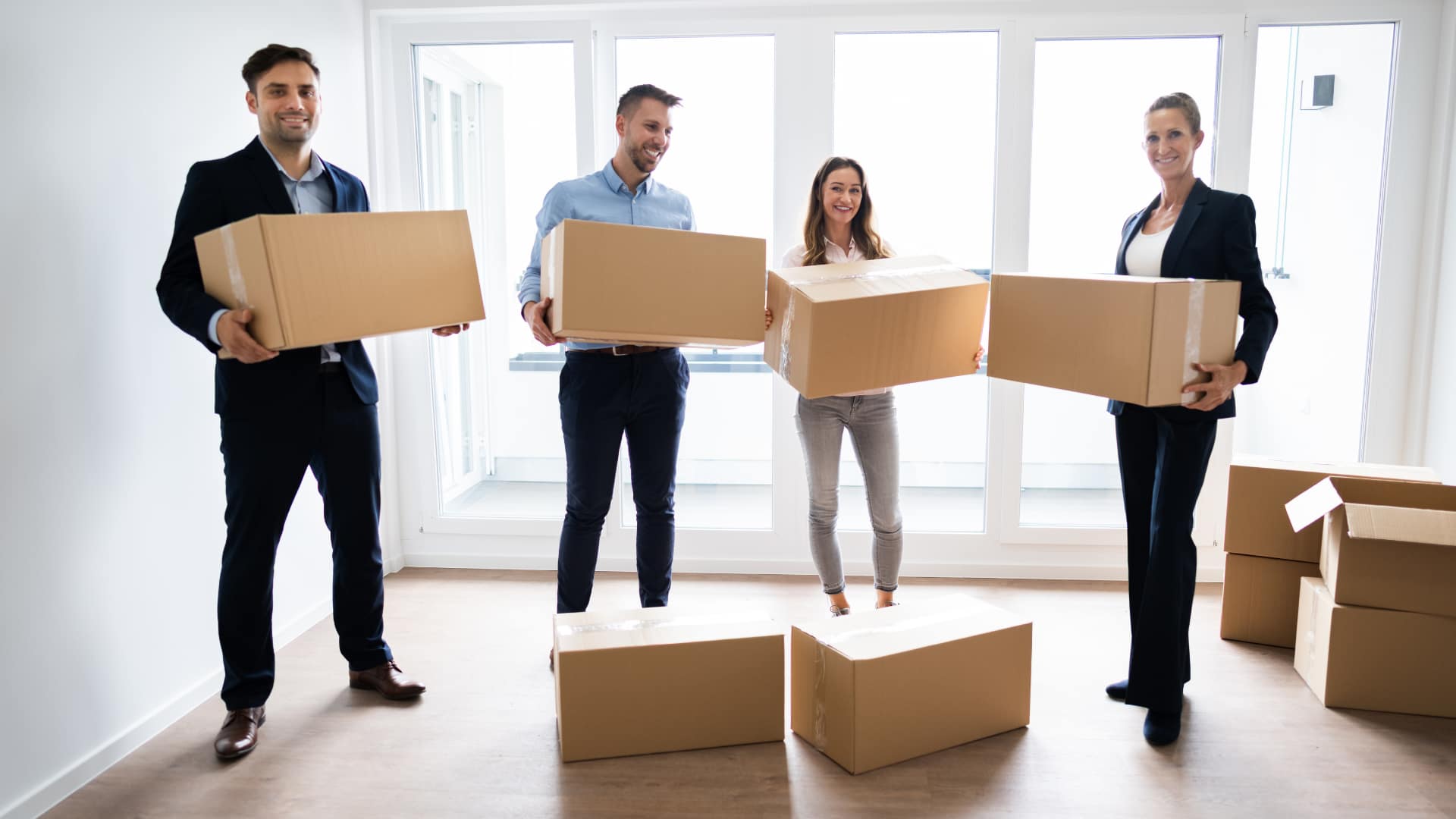 A group of coworkers holding boxes in a new office