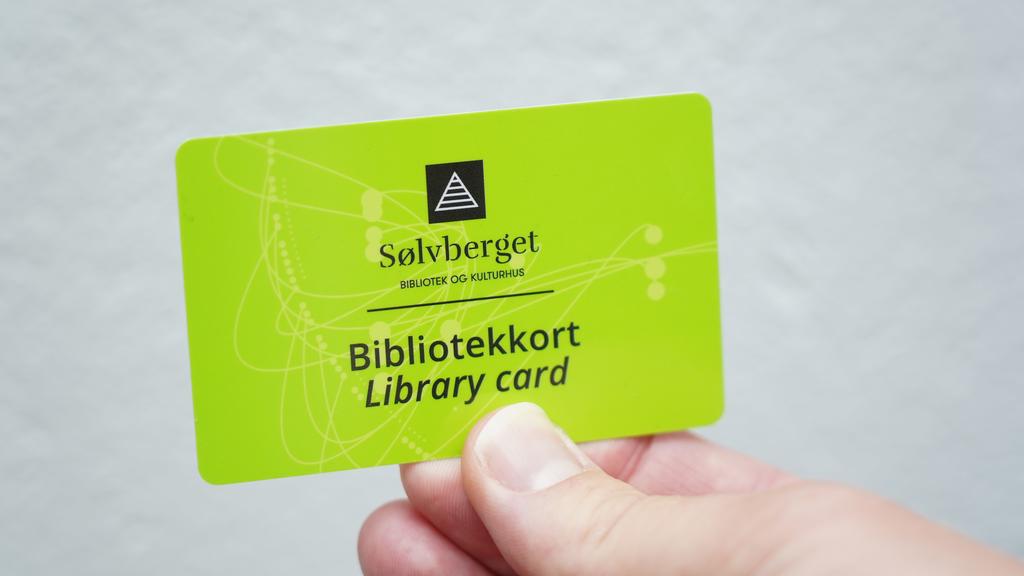 En hånd holder et grønt Sølvberget biblotekkort