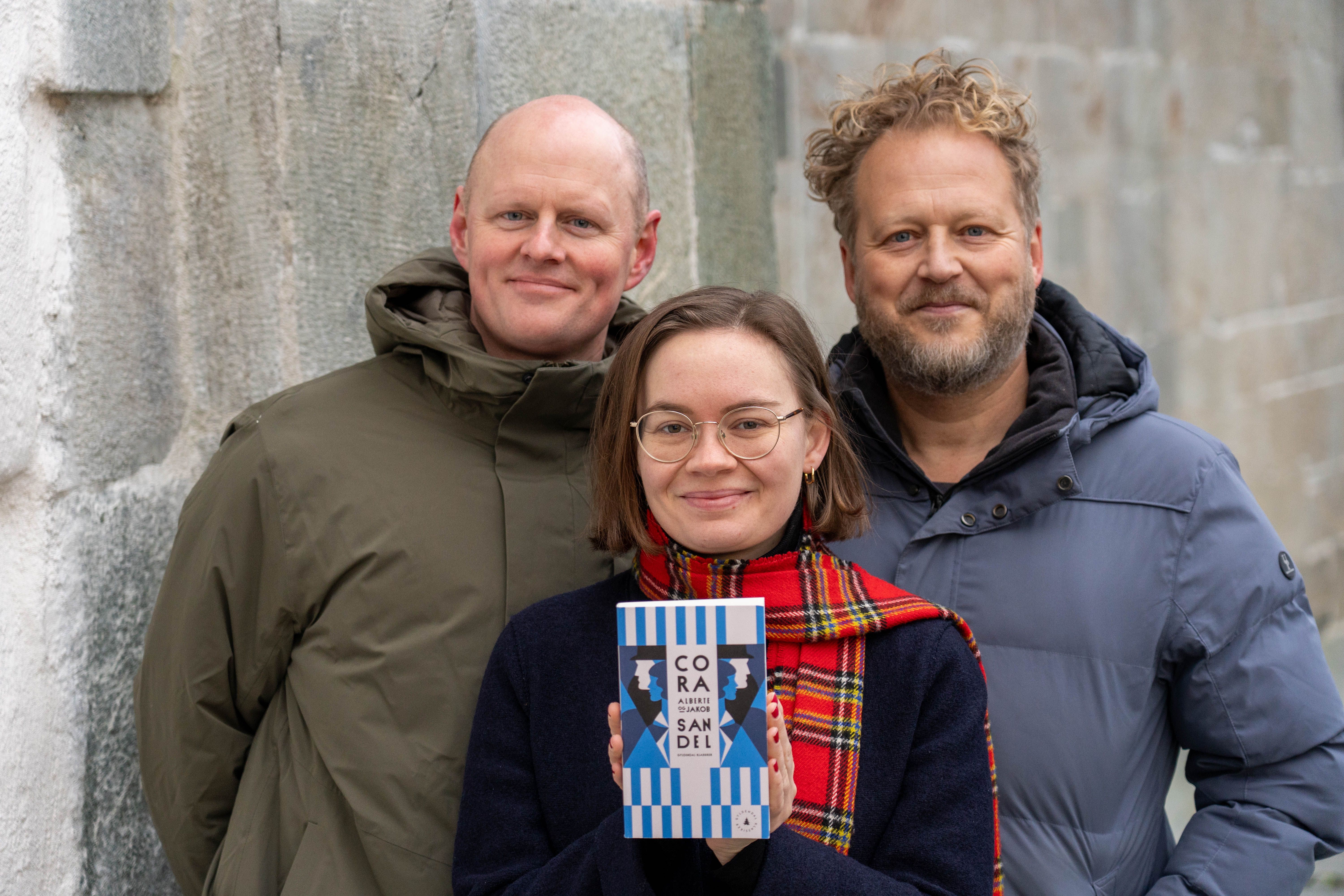 Åsmund Ådnøy, Ruth Stokke Haaland og Tomas Gustafsson med boka Alberte og Jakob av Cora Sandel