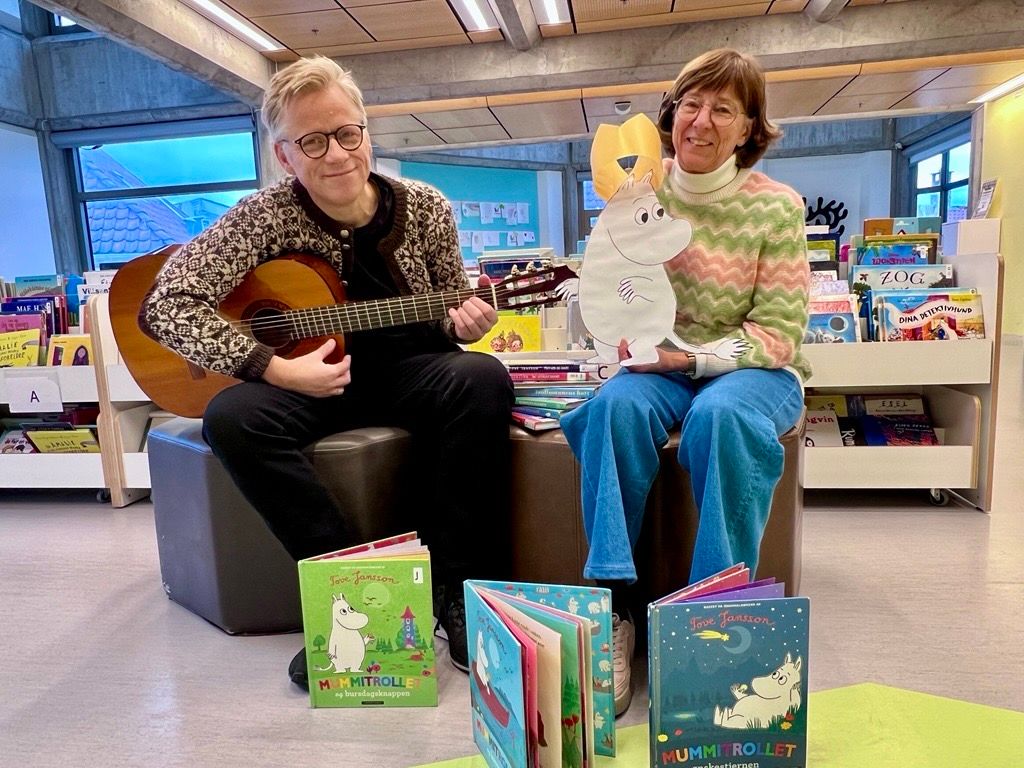 Foto av Ebbe Helberg og Eli Gunn Buvik som viser bøker og mumitrollet med bursdagskrone