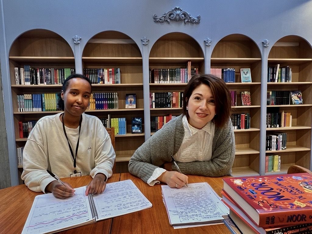 Foto av to kvinnelige ansatte som skriver tekster i biblioteket.