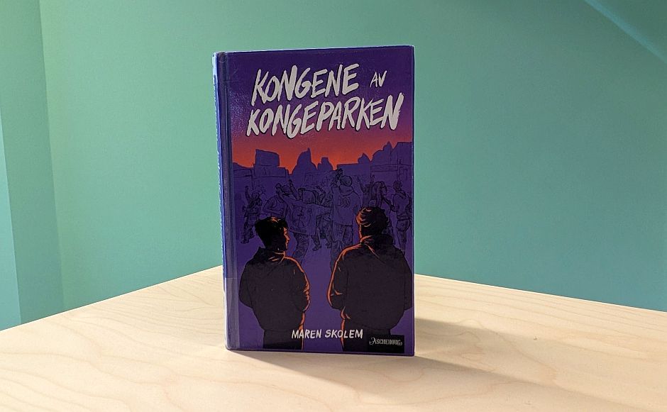 Boka Kongene av Kongeparken stående på en bokhylle med grønn vegg bak