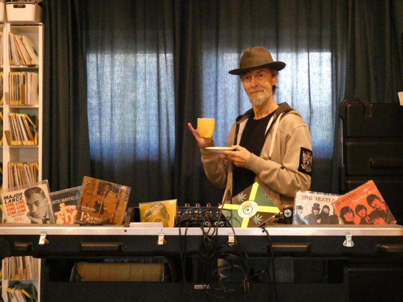 William Helvik holder kaffekopp bak en skranke med mange plater