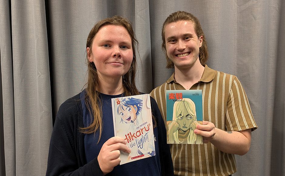 Einar Hildonen og Mette Henriksen holder mangabøker foran grå gardin