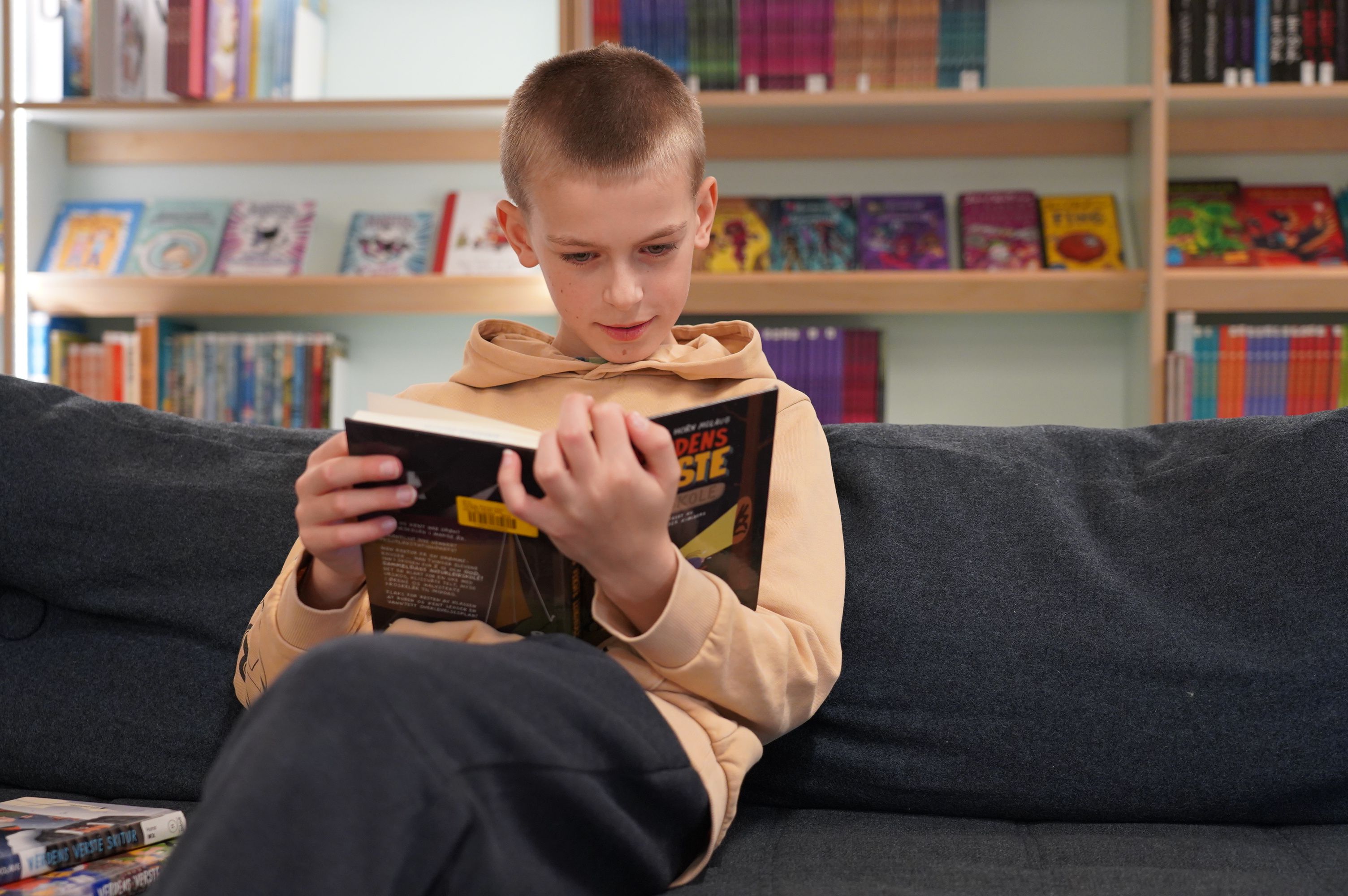 Gutt leser bok på biblioteket 