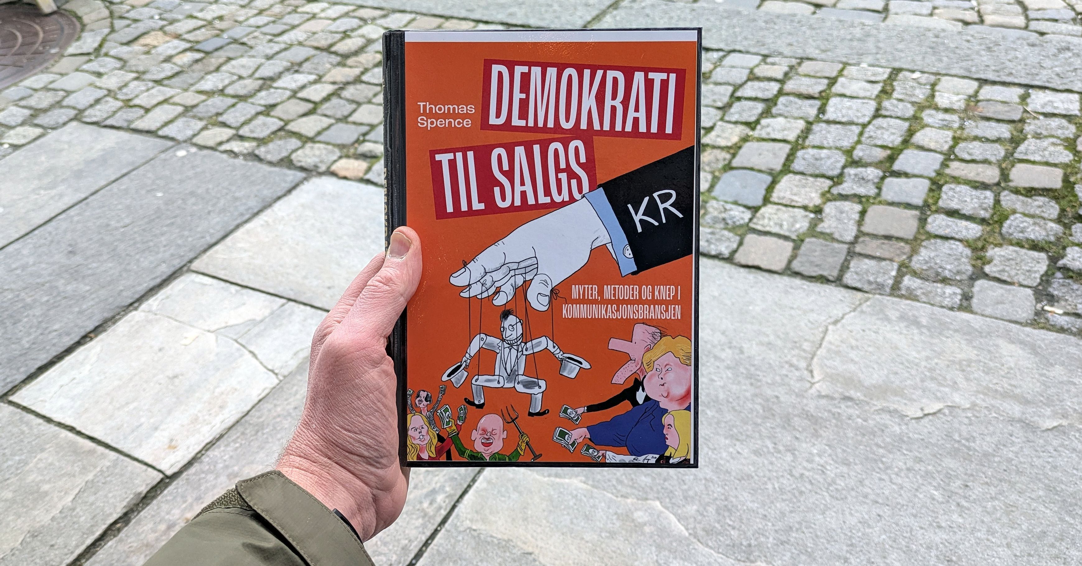 Boka Demokrati til salgs holdt foran et gateløp
