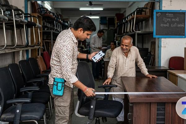 Buyer inspecting a used office chair and desk in Gujarat with Zutilo marketplace branding Buyer inspecting a used office chair and desk in Gujarat with Zutilo marketplace branding