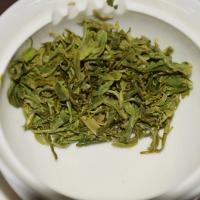 Quality inspection of Biluochun green tea, showing tender and fresh wet leaves in a white tasting cup.