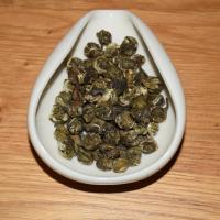 Premium Jasmine Dragon Pearl green tea for global bulk sourcing, displaying tightly hand-rolled tea pearls in a white ceramic dish on a wooden surface.