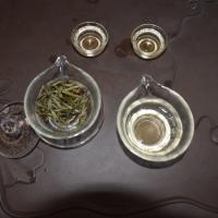 Top-down view of brewed Silver Needle white tea in glass teaware on a dark tea tray, highlighting the clear infusion.