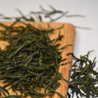 Wholesale organic Enshi Yulu steamed green tea, showcasing premium needle-like dark green leaves on a natural wood tray.
