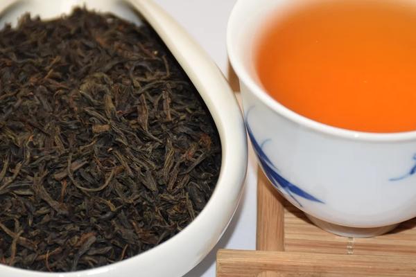 Wholesale premium Keemun Gongfu (Qimen) black tea displaying tightly twisted dry leaves and bright orange-red liquor.