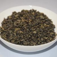 Wholesale organic Gunpowder green tea, displaying tightly rolled dark green pellets in a white ceramic bowl.