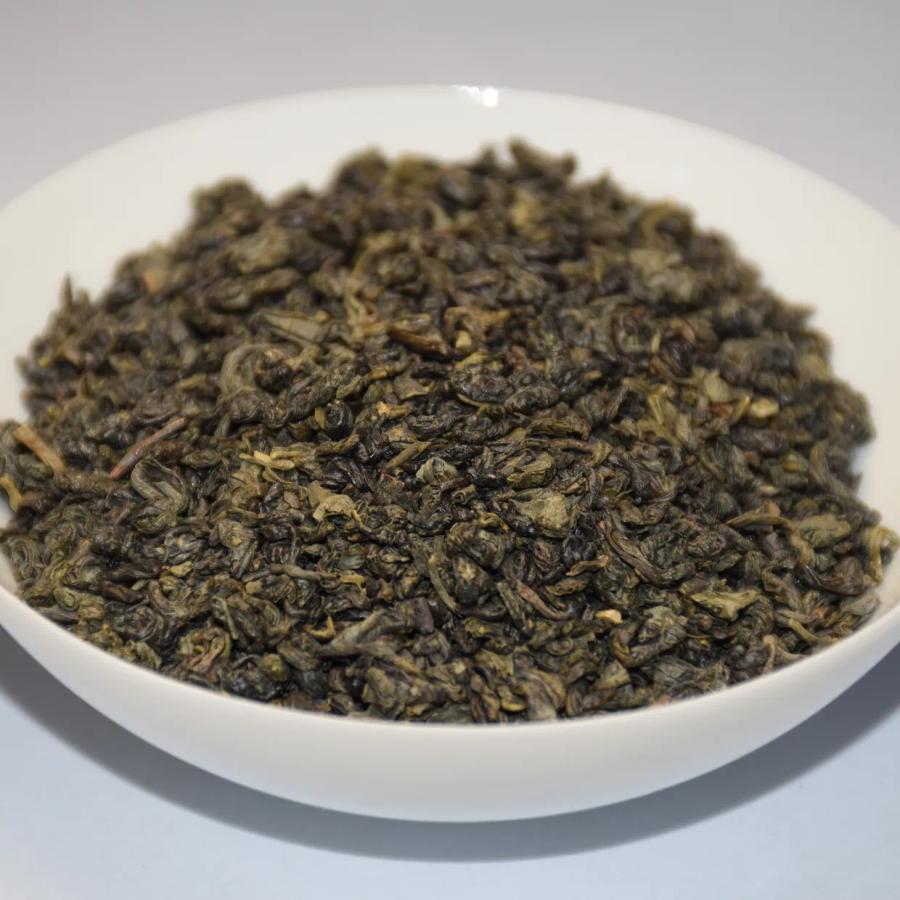Wholesale organic Gunpowder green tea, displaying tightly rolled dark green pellets in a white ceramic bowl.