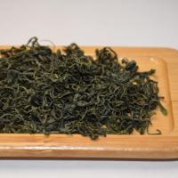 Professional inspection of wholesale Lushan Yunwu green tea, showing tight, curly dry leaves with prominent silver pekoe in a white cup.