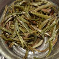 Quality evaluation of Guangxi Silver Needle white tea, showing tender, stout, and fresh infused buds in a glass cup.