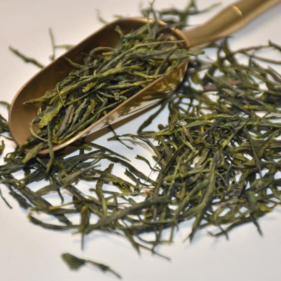 Wholesale organic Enshi Yulu (steamed green tea), featuring premium needle-like dark green dry leaves and a golden tea scoop.
