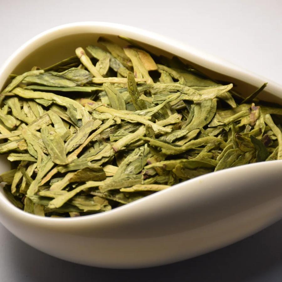 Wholesale premium flat Dragon Well green tea leaves showing vibrant spring harvest color.