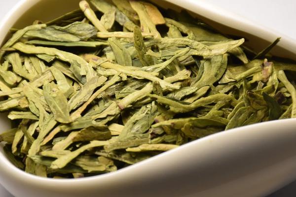 Wholesale premium flat Dragon Well green tea leaves showing vibrant spring harvest color.
