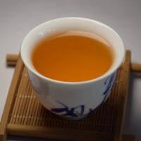 Quality evaluation of wholesale Shaoguan Honey Black Tea infusion, displaying a bright and clear amber liquor.