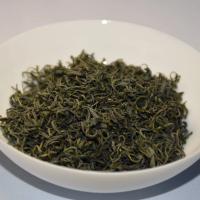 Professional quality check of wholesale Lushan Yunwu green tea, showing tender curly dry leaves with abundant silver pekoe in a dark ceramic bowl.