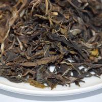 Quality inspection of wholesale EU-compliant raw Pu-erh tea, showing clean, stout, and loosely twisted dry leaves on a white plate.