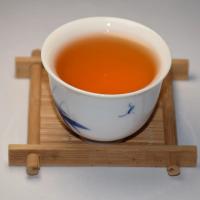 Professional evaluation of wholesale Keemun Gongfu black tea infusion, showing a bright orange-red liquor with a golden ring.