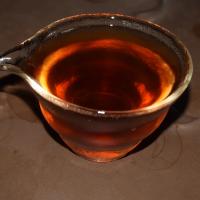 Macro close-up of authentic organic Shou Pu-erh tea soup in a glass pitcher, highlighting its clear, vibrant dark red color.