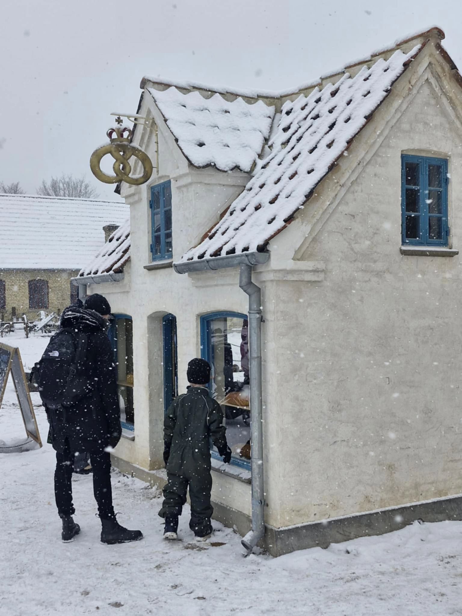 Adult and child looking into the bakery building in snowy weather